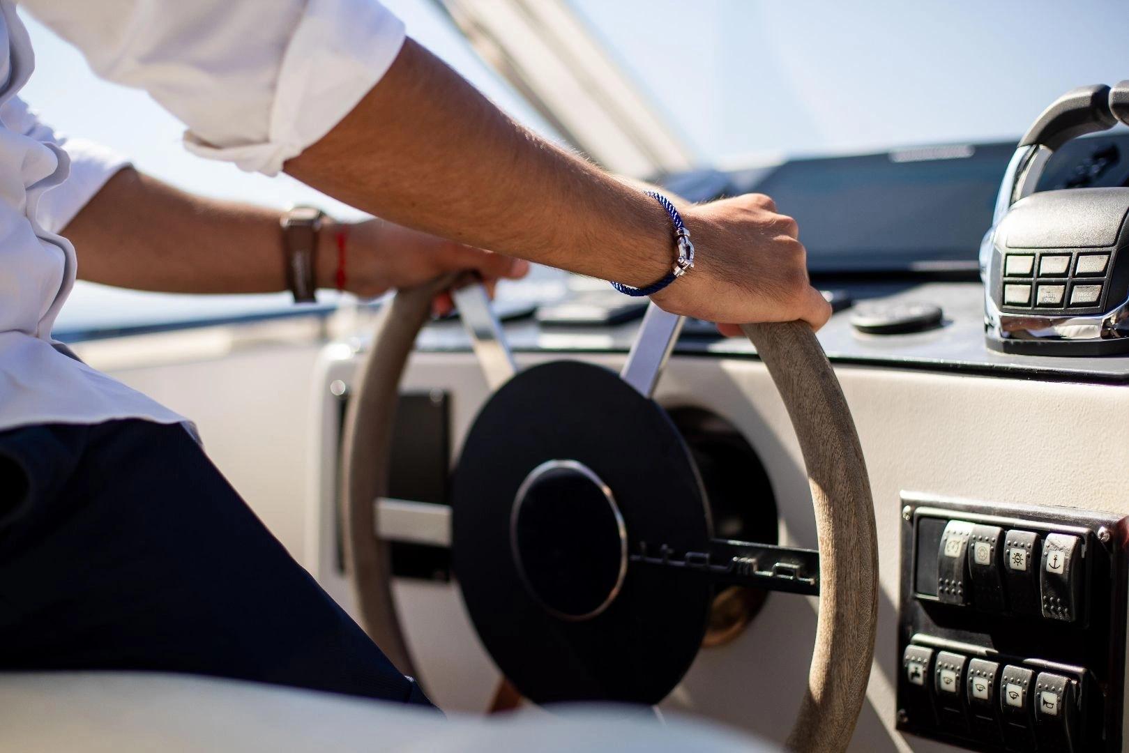 Homme tenant le volant d'un bateau avec vue sur le tableau de bord et la mer