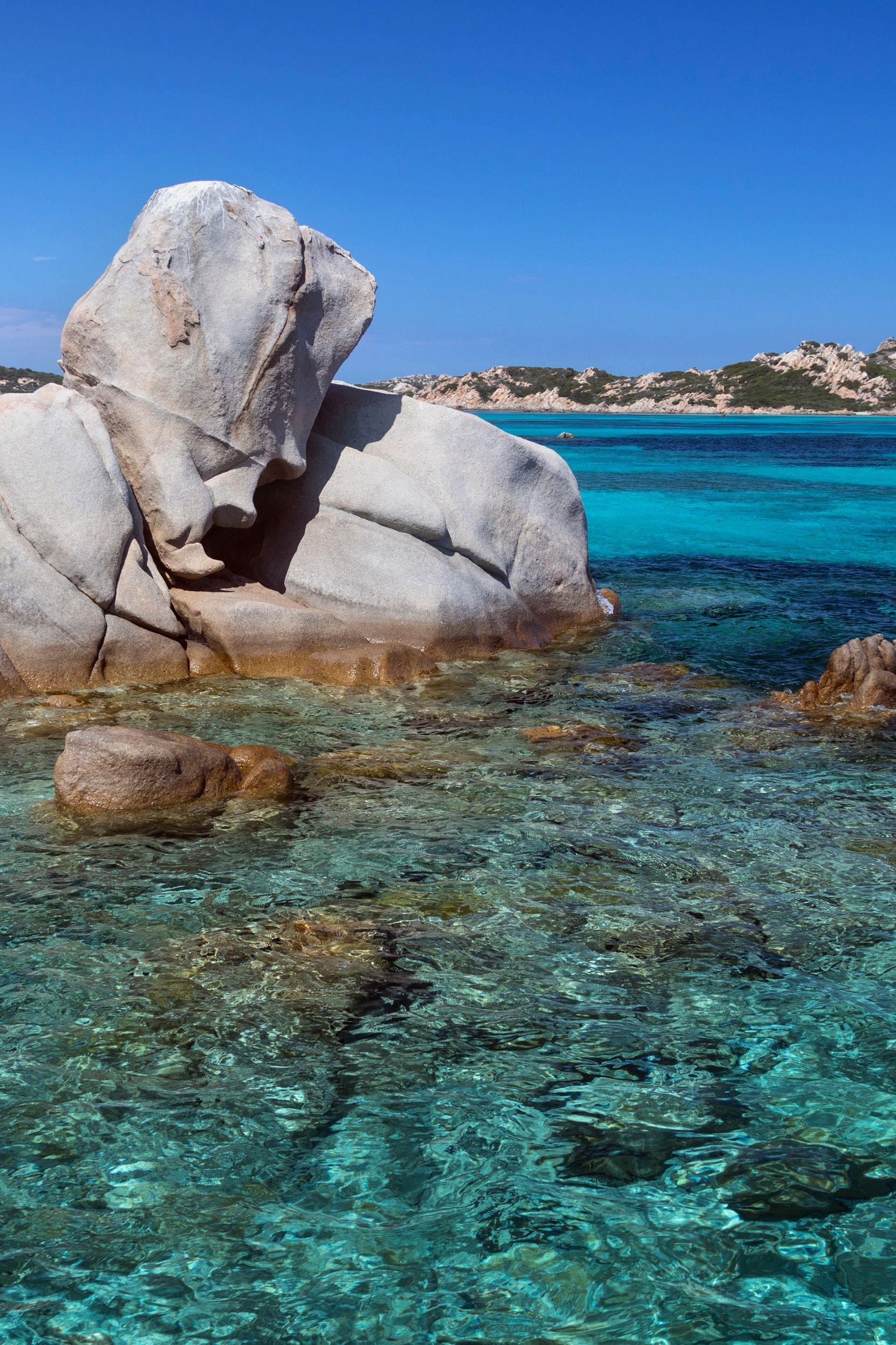 Rocher granit blanc en bord de mer turquoise avec bateau à l'horizon