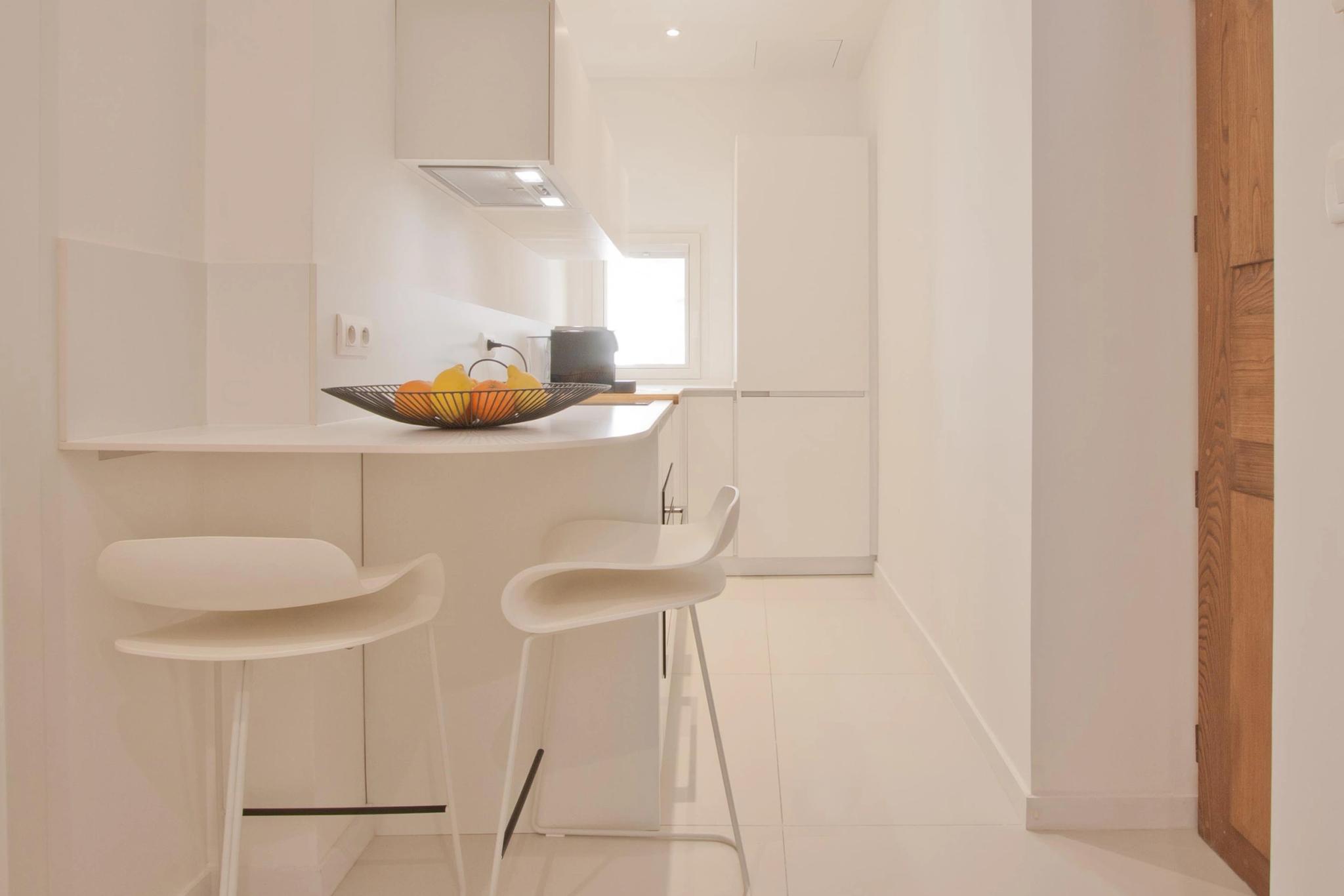 Cuisine moderne et épurée d'appartements de luxe avec îlot blanc et tabourets design
