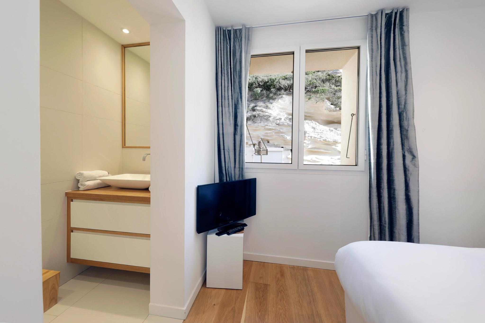 Chambre moderne d'une résidence de luxe avec vue sur la mer et salle de bain attenante