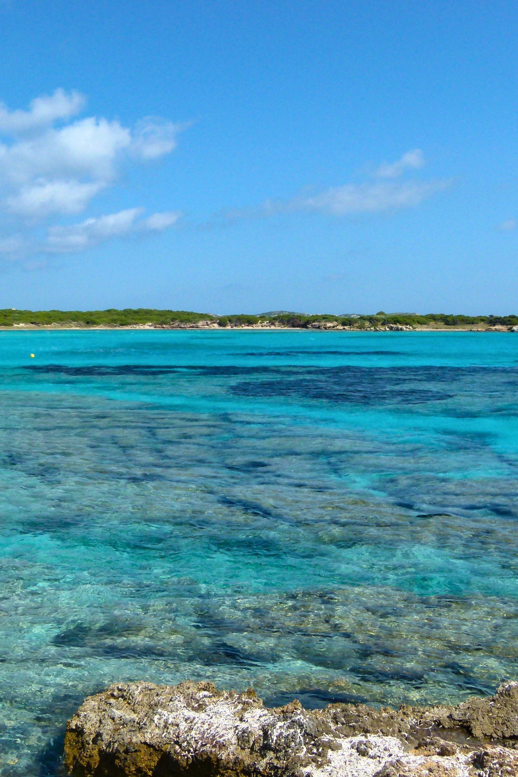 Crique turquoise avec bateau ancré près de la côte rocheuse et végétation méditerranéenne