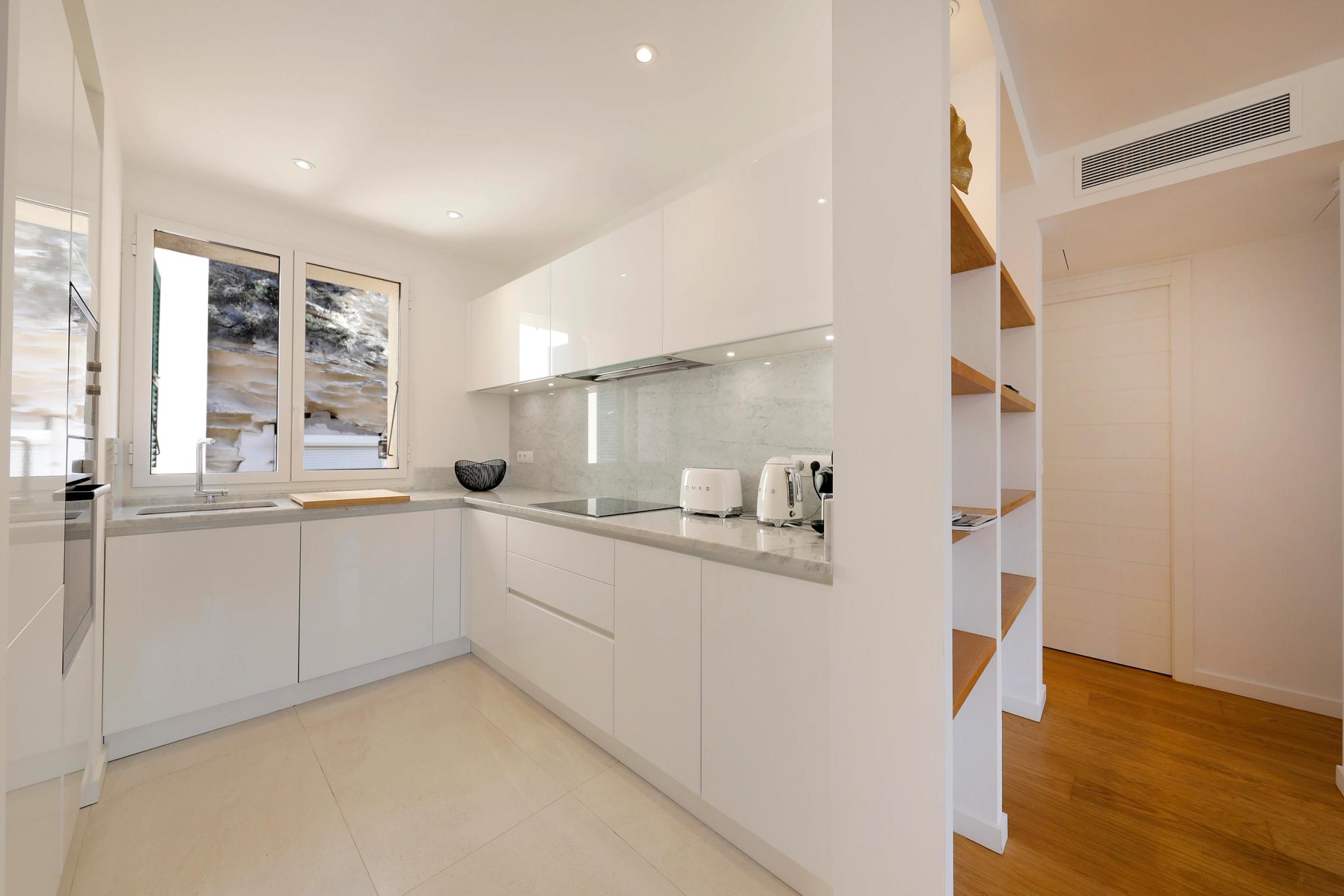 Cuisine moderne et lumineuse d'une résidence de luxe avec façades blanches et plan de travail gris