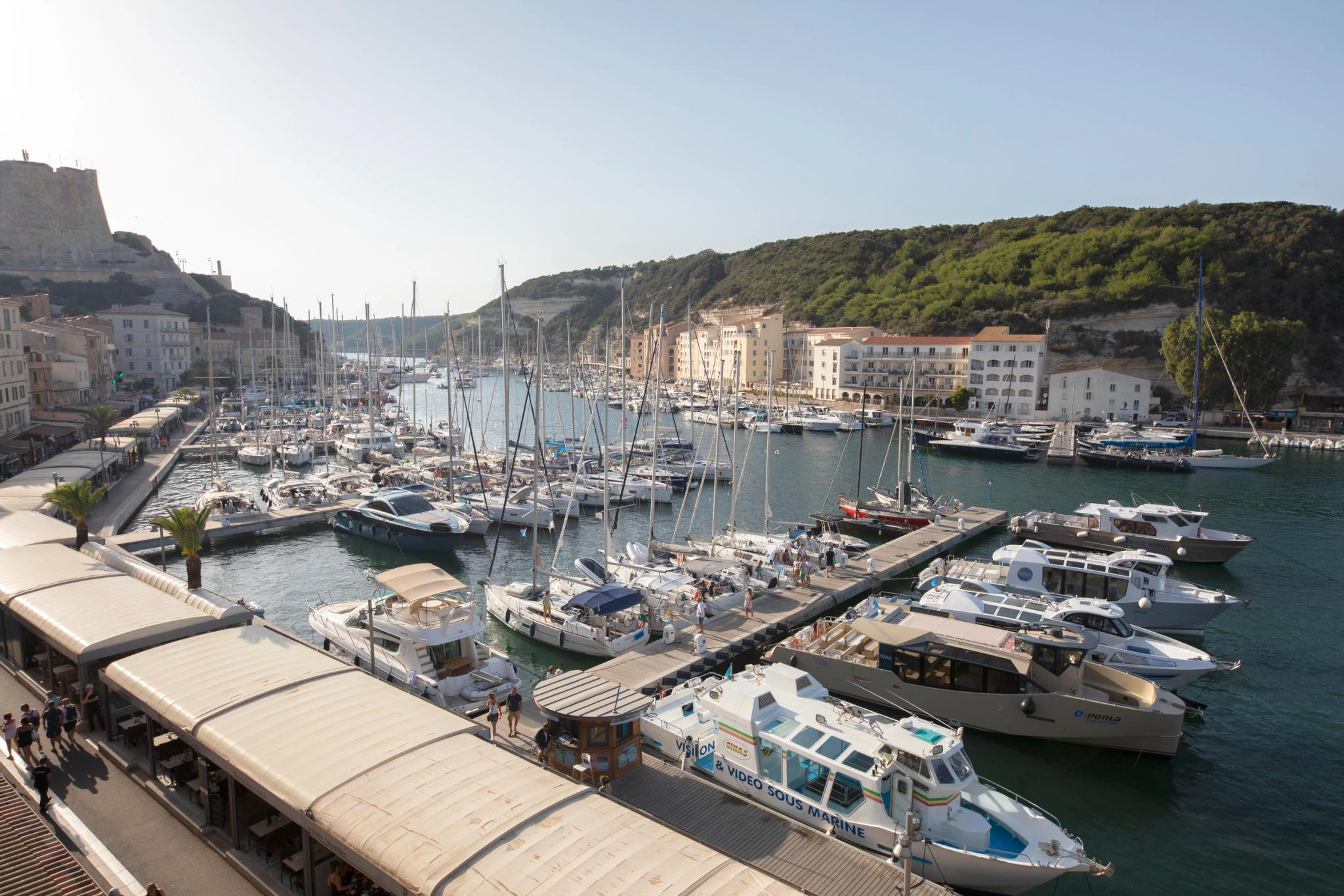Marina côtière avec voiliers, résidence de luxe en bord de mer et collines boisées