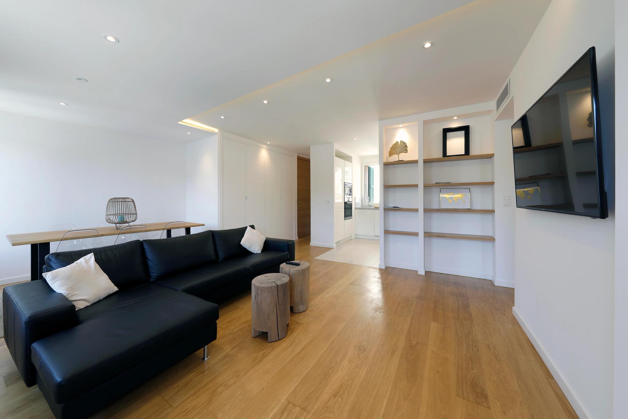 Spacieux salon moderne d'une résidence de luxe avec canapé noir, écran TV et étagères design