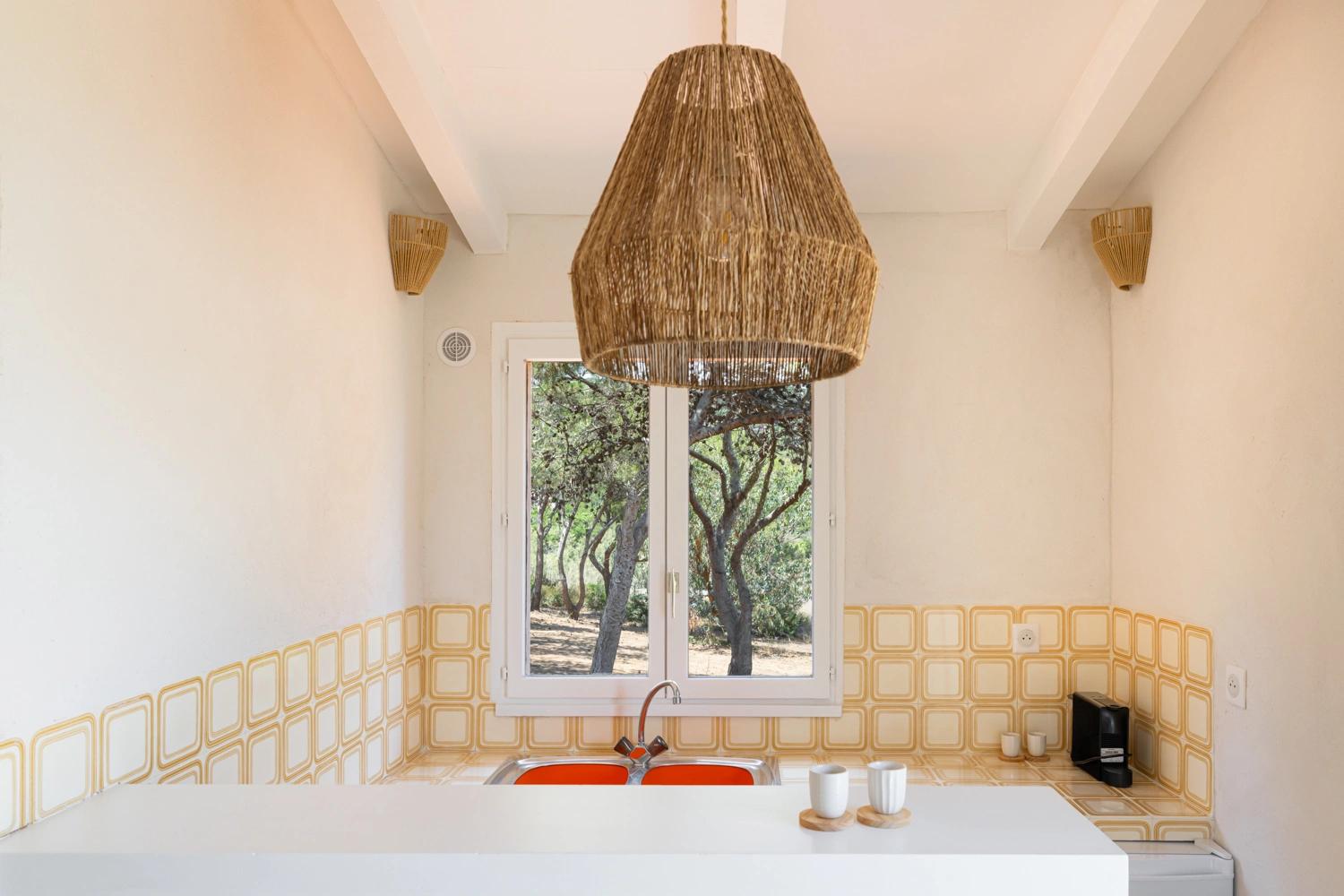 Cuisine moderne d'une résidence de luxe avec lustre en rotin et vue sur jardin