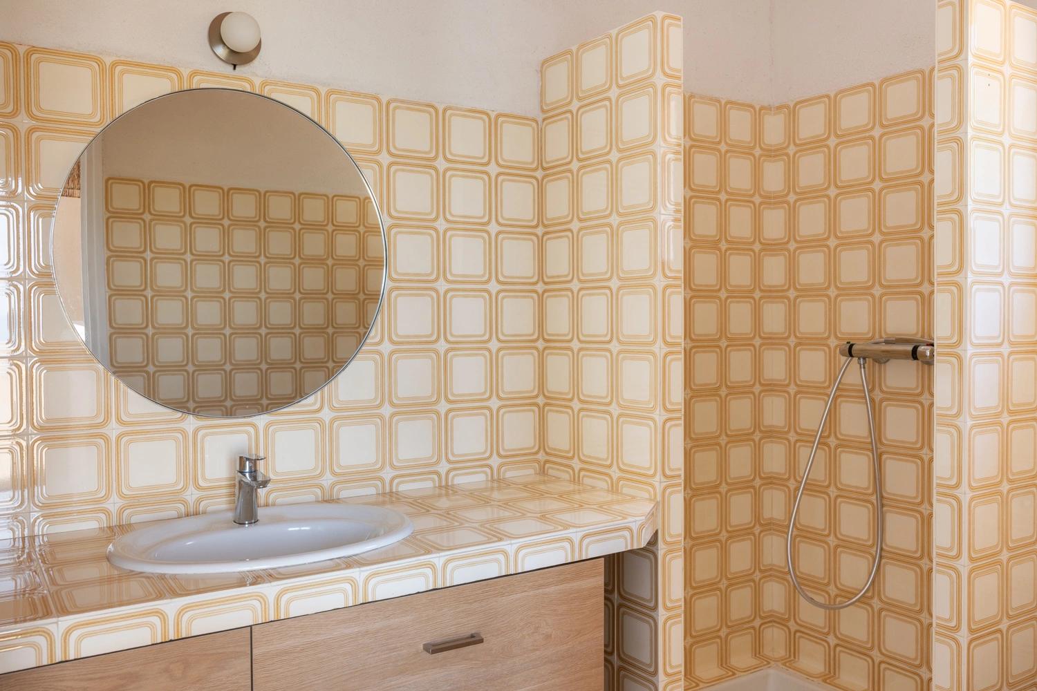 Salle de bain moderne d'une résidence de luxe avec carrelage géométrique doré et mobilier élégant