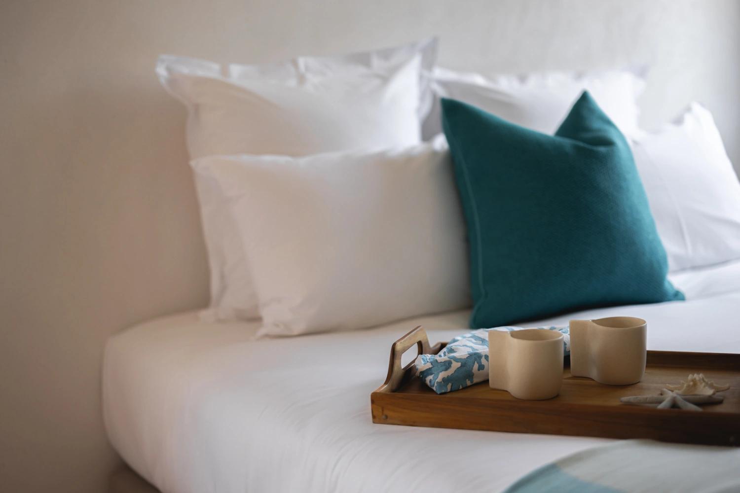 Chambre de résidence de luxe avec lit blanc, oreillers et plateau de bienvenue
