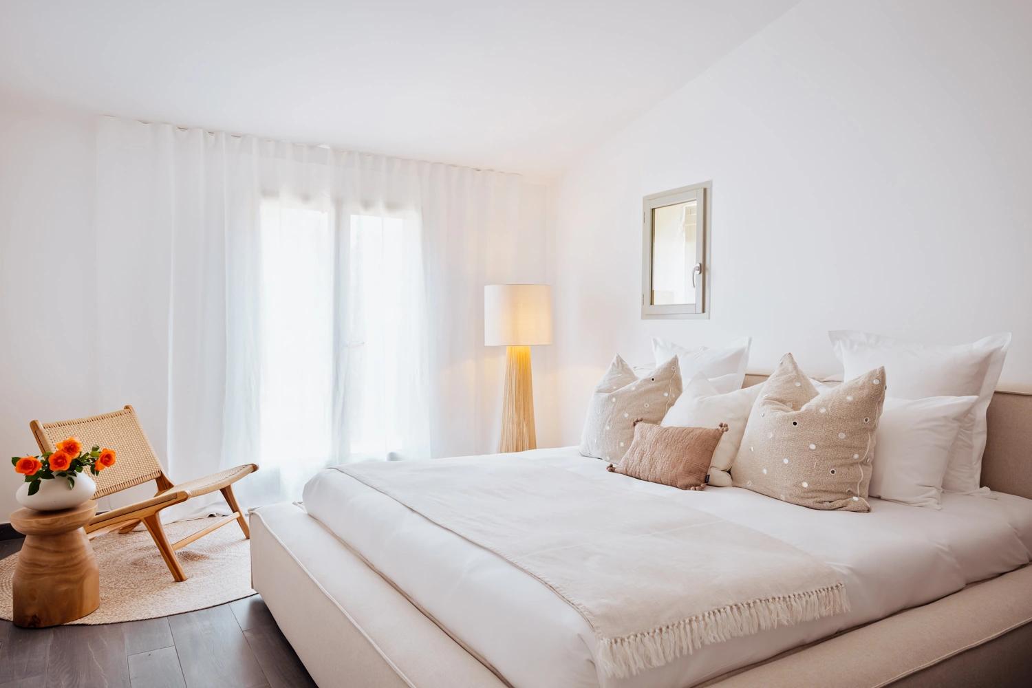 Chambre élégante d'une résidence de luxe avec lit blanc et coussins beige