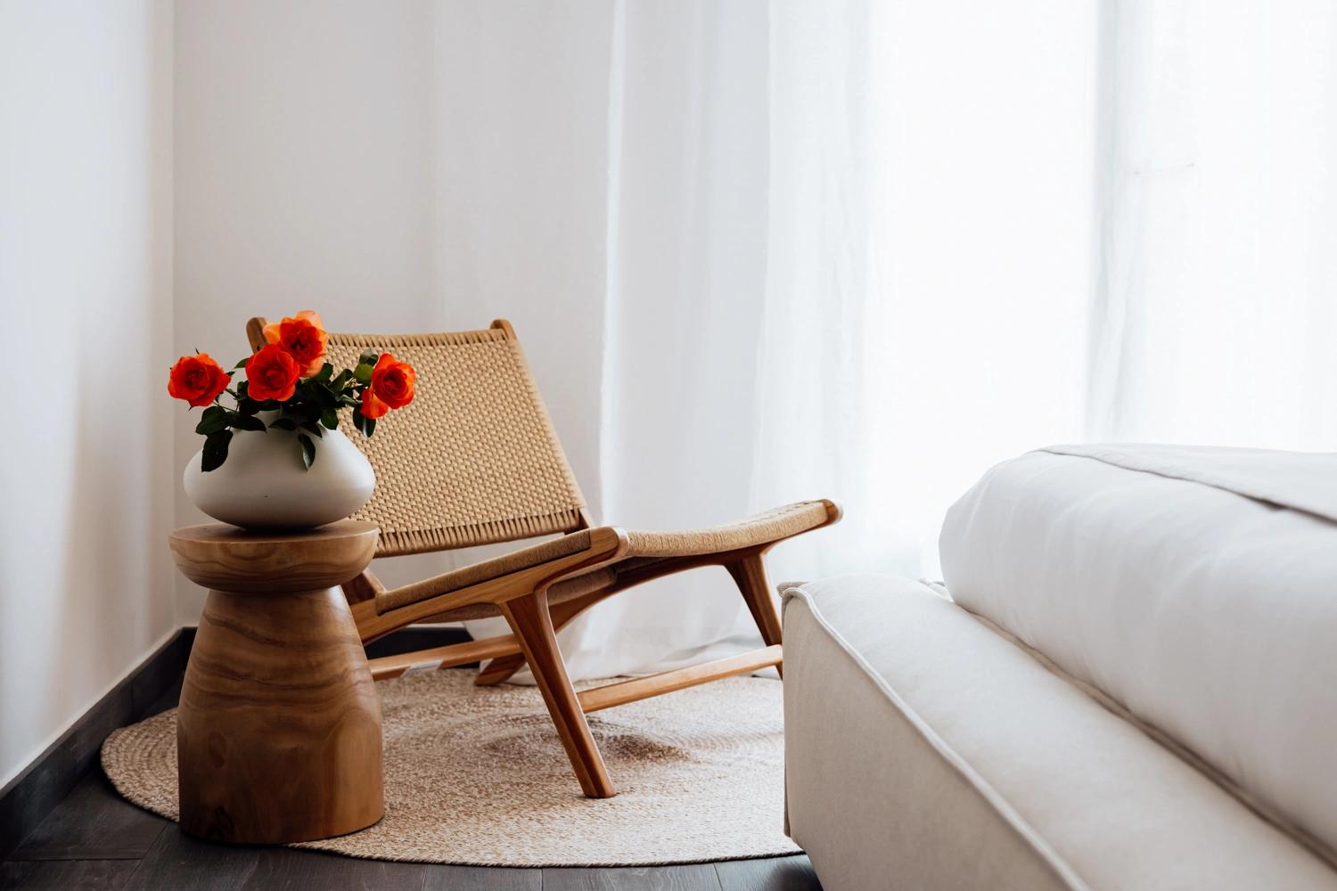 Chambre de résidence de luxe avec chaise en bois, fleurs rouges et décoration épurée