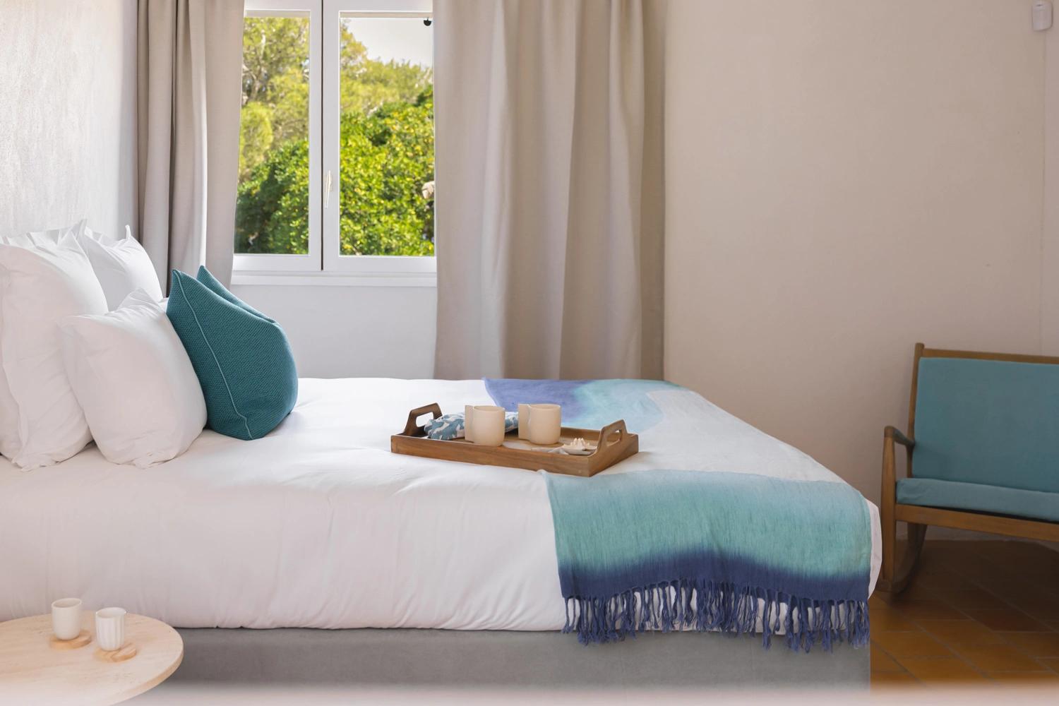 Chambre élégante d'une résidence de luxe avec lit blanc et accessoires teal