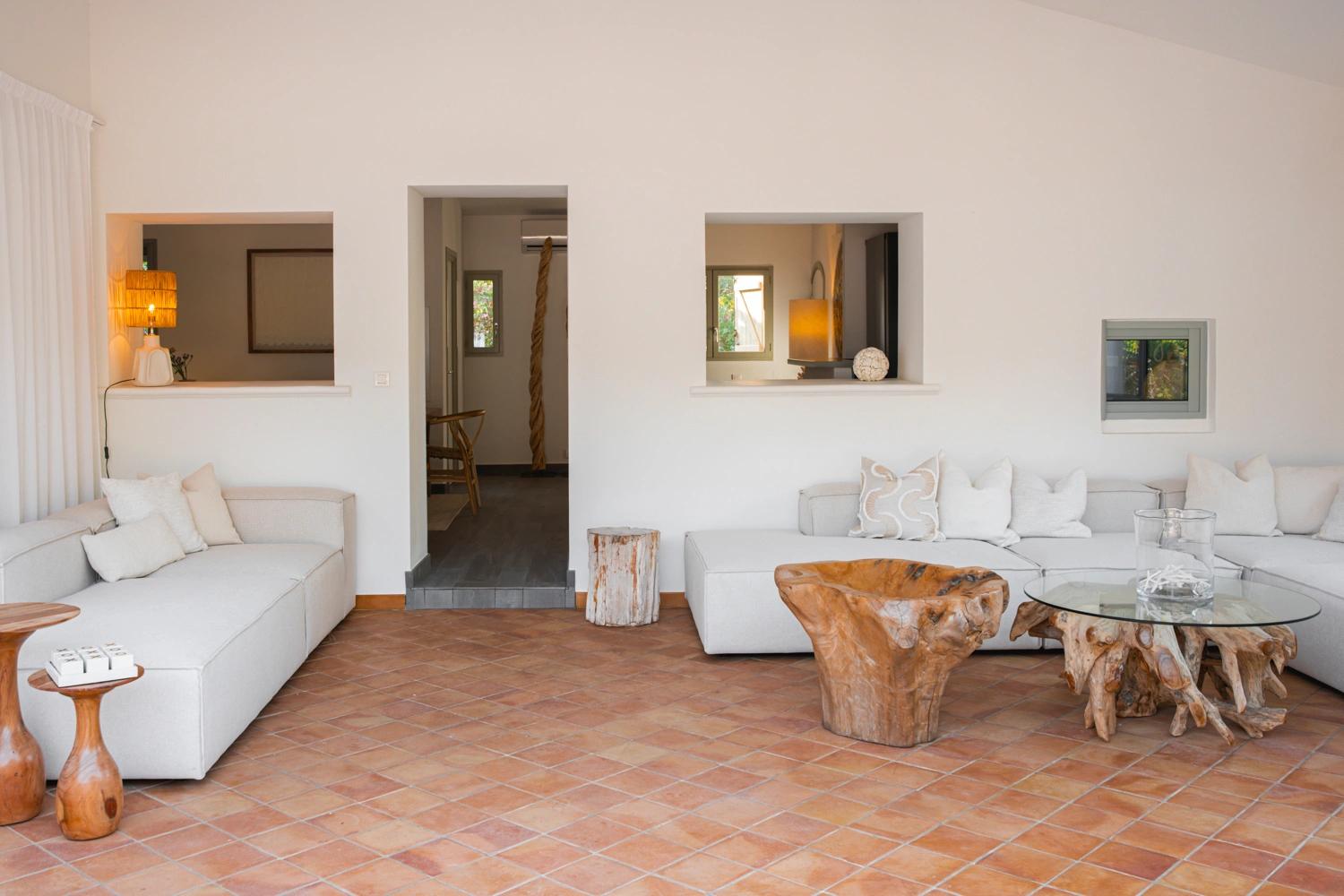 Salon spacieux d'une résidence de luxe avec canapés blancs et sol en terre cuite