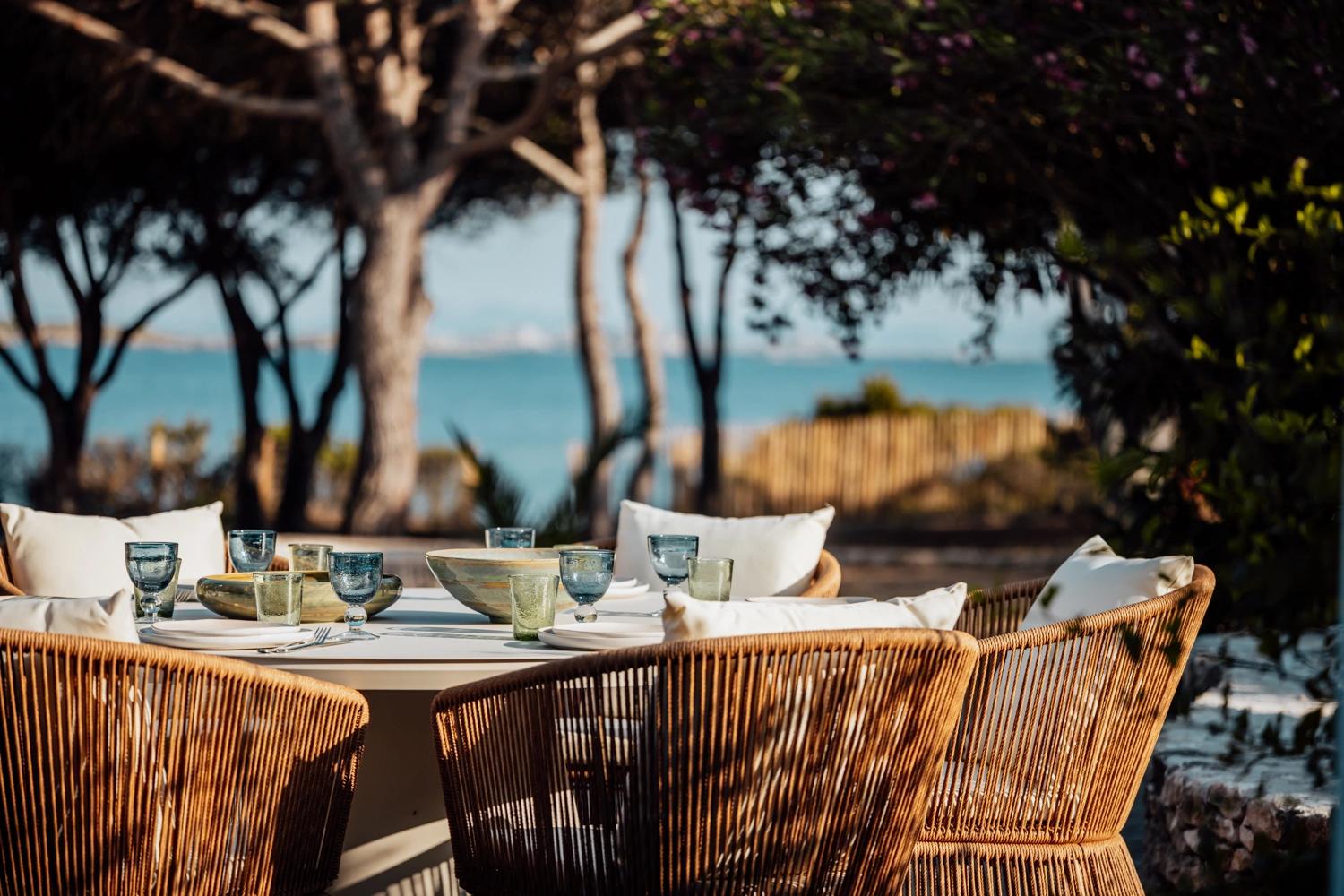 Résidence de luxe avec table élégante face à la mer et chaises en rotin